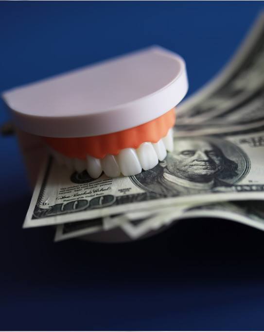 An artificial jaw mockup biting a few hundred-dollar bills