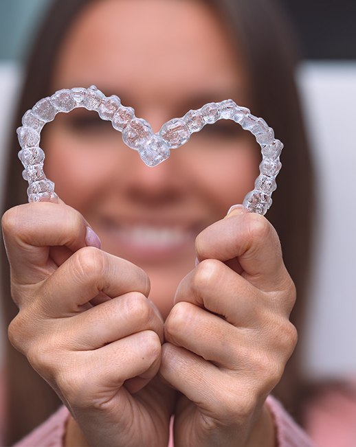 Woman holding Invisalign trays in the shape of a heart