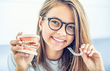 Girl holding sample braces in one hand and Invisalign in the other