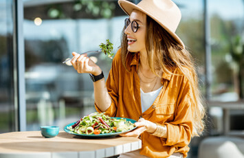 woman smiling while eating lunch outside