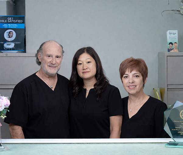 Smiling man and woman sitting together on beach after visiting New York dental office
