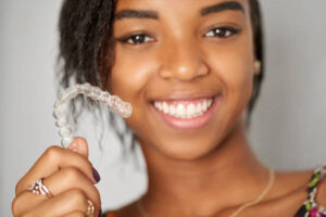 Smiling young woman holding a clear aligner