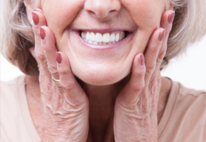 Close up of senior woman smiling and pressing her hands to her face