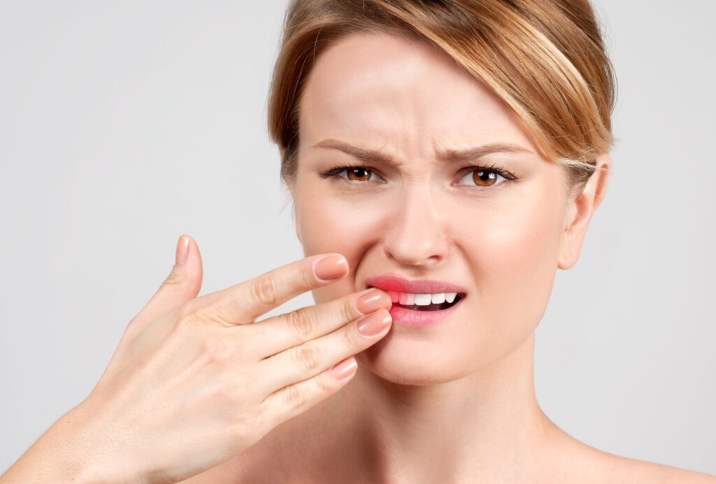 Woman with brown eyes touching her loose tooth